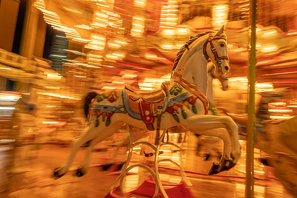 A dynamic and blurred image of a carousel horse in motion, showing the versatility of Tamron concert photography lenses