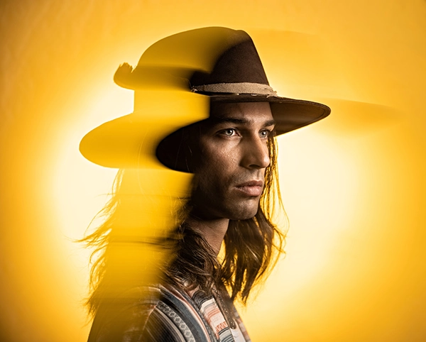 A creative portrait featuring a cinematic photography double exposure effect with blurred yellow outlines that emphasize the subject’s profile against a bright yellow background. 