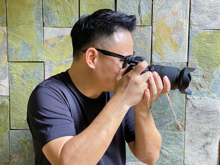 Photo of a Man Holding a Tamron 28-200mm Lens