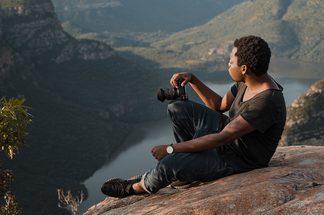 Photo of a Man Holding a Camera on a Cliff of a Mountain Shot by Tamron 11-20mm F2.8