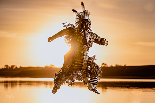 Tribal dancer at sunset, with river at golden hour in the background