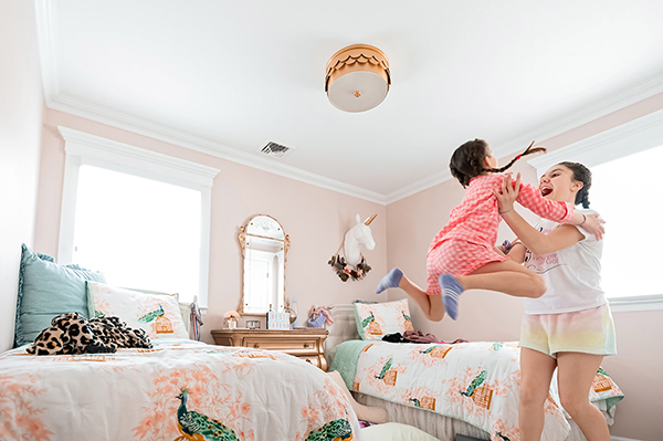 Sister jumping off her bed into her sister's arms © Vanessa Guzzo